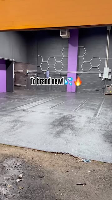 A freshly painted grey concrete floor in a wide open bay with purple columns and hexagon lights on the wall behind.